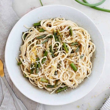 garlic scape pasta topped with lemon zest and cheese in a serving bowl