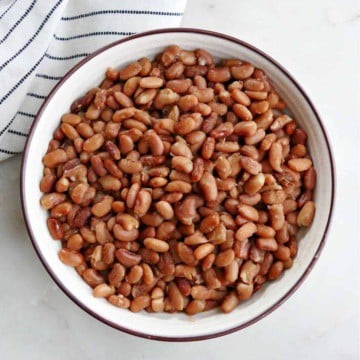 Instant Pot pinto beans in a serving bowl on a counter next to a striped napkin