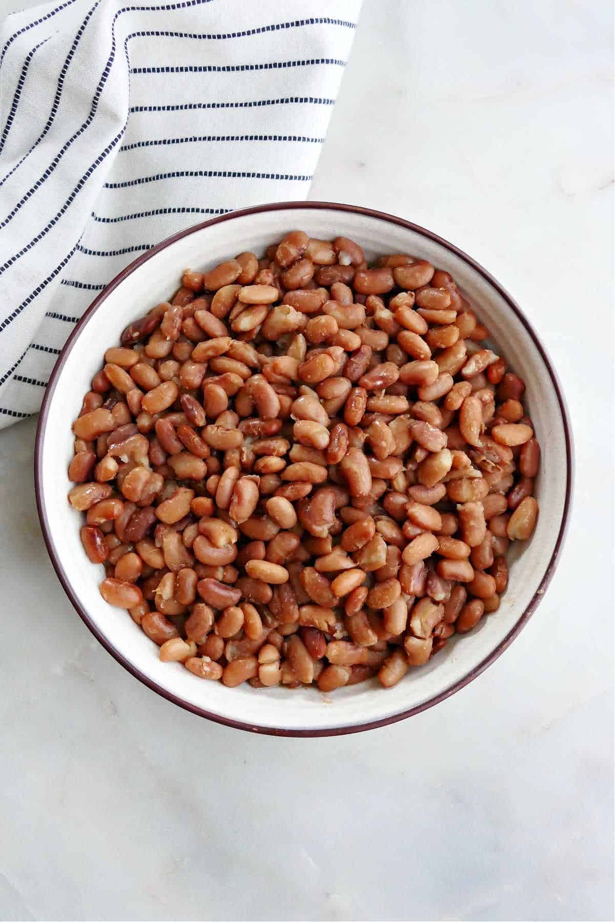 Instant Pot pinto beans in a serving bowl on a counter next to a striped napkin