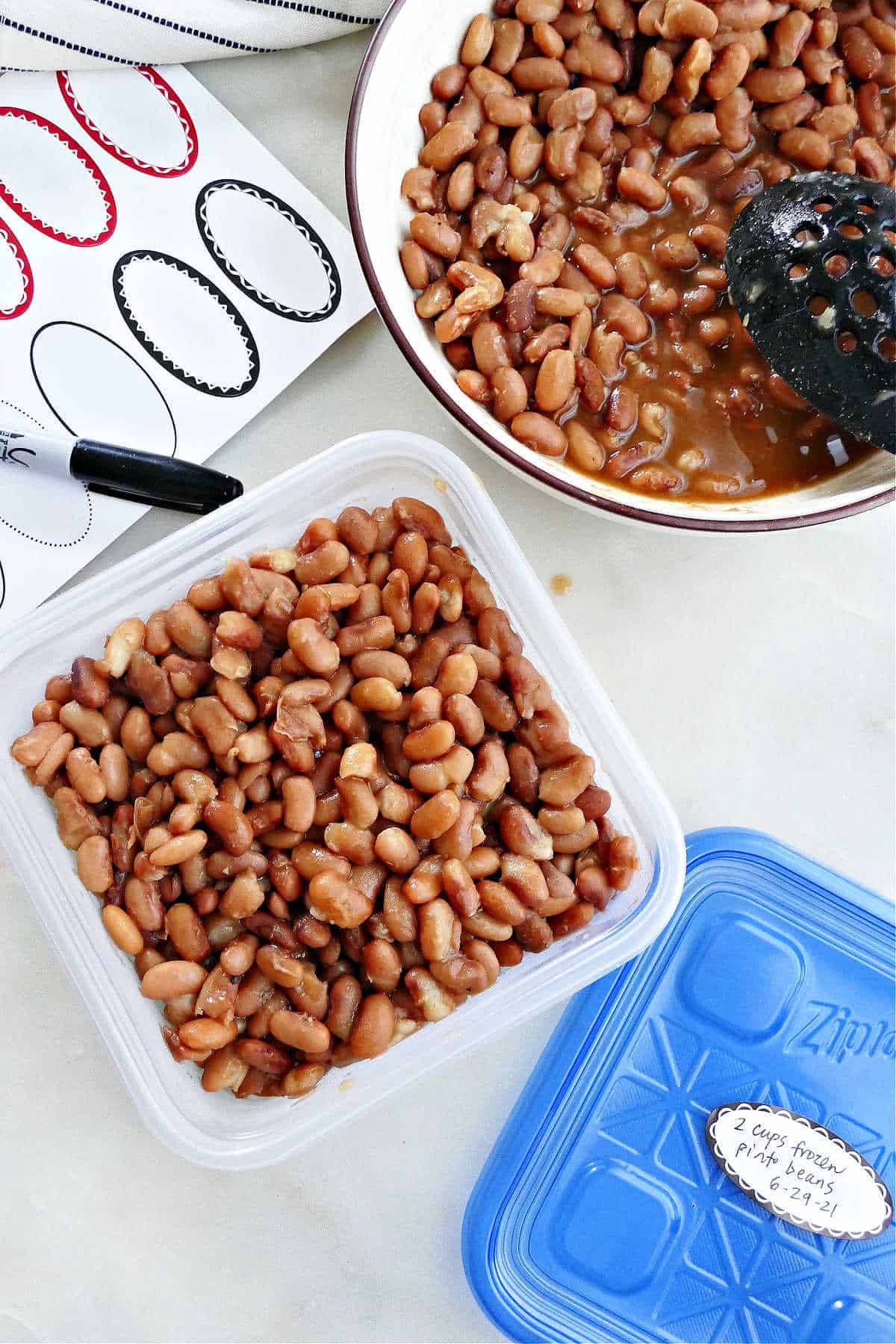 Instant Pot pinto beans in a plastic container next to labels and a pen