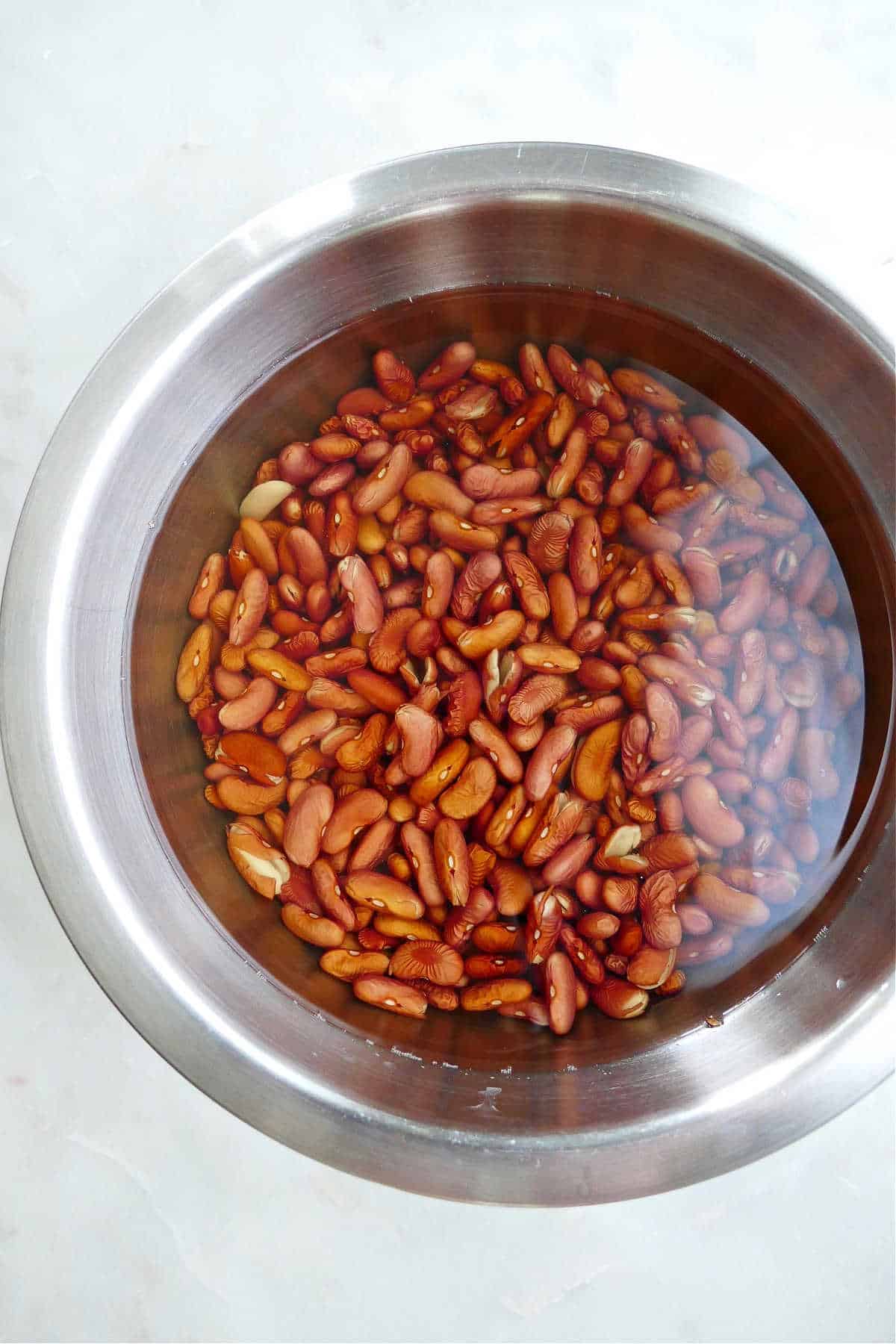 red kidney beans soaking in a bowl full of water on a counter