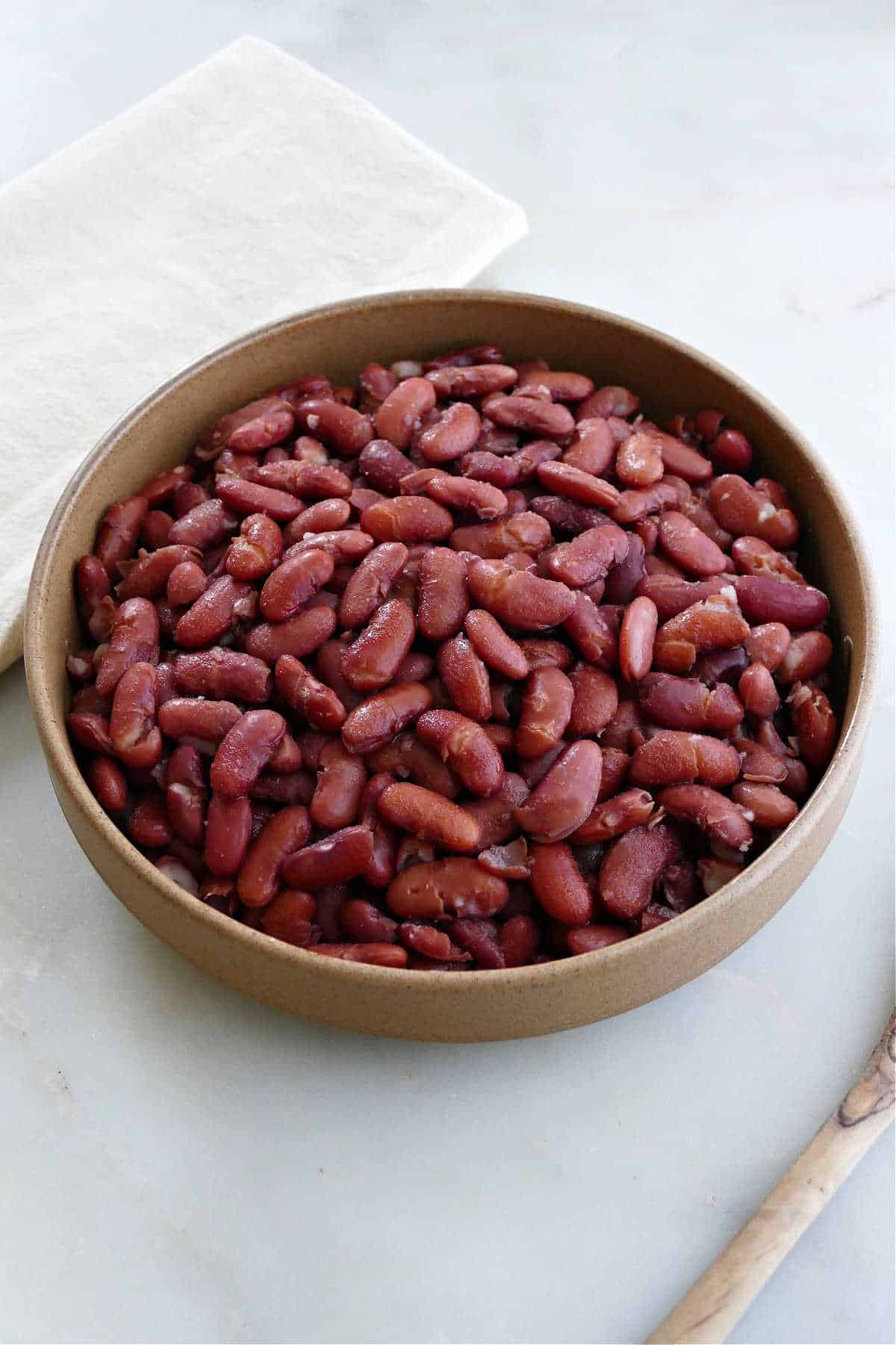 cooked kidney beans on a counter next to spoon and napkin