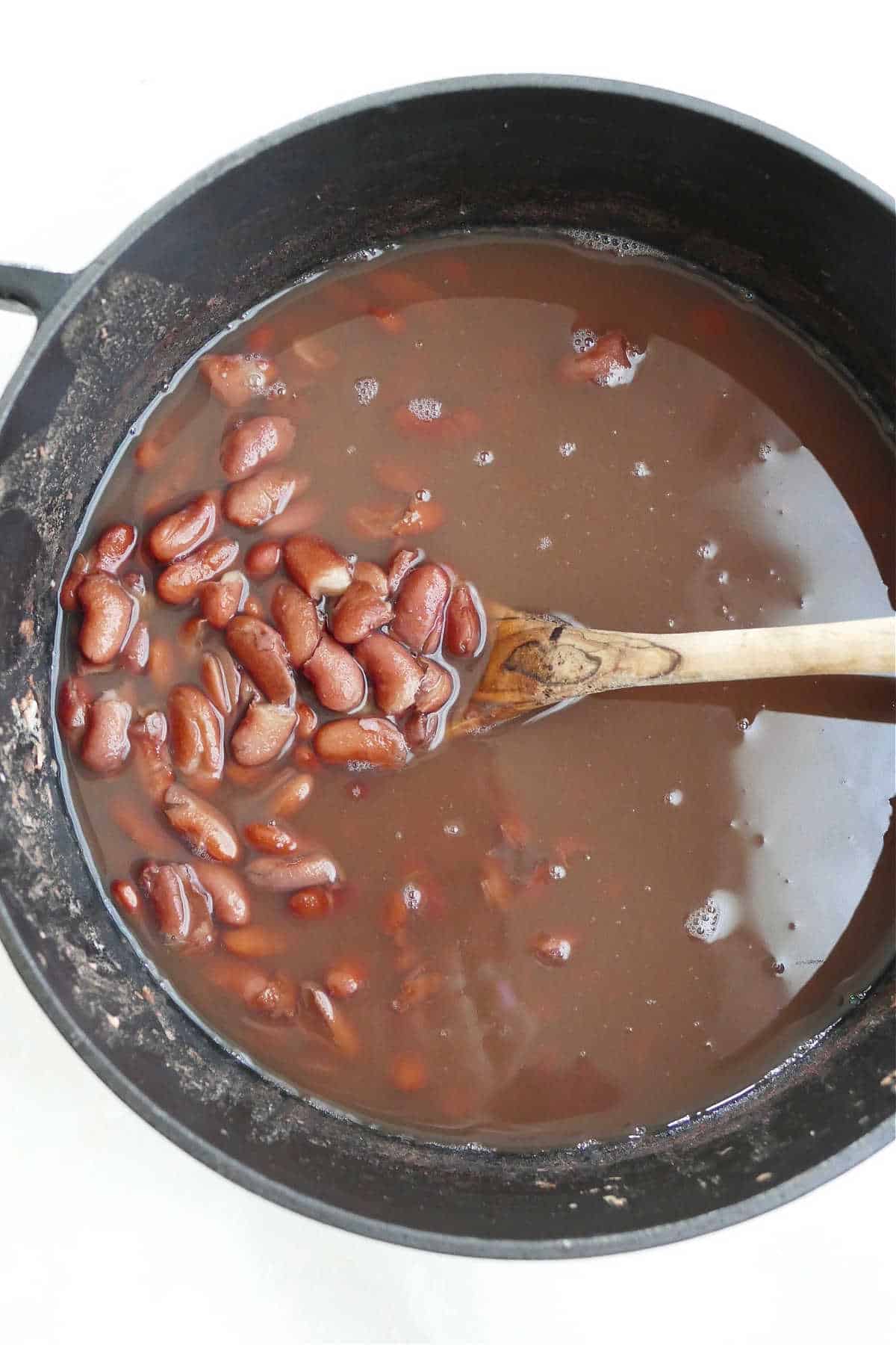 cooked kidney beans in a Dutch oven with a wooden spoon on a counter