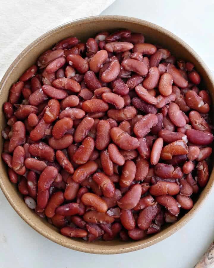 cooked kidney beans in a serving bowl next to a spoon and napkin