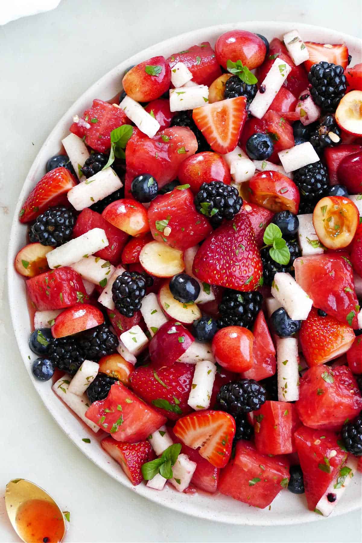 red, white, and blue fruit salad with a honey lime mint dressing on a serving platter