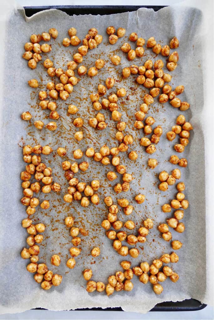 crispy roasted chickpeas spread out on a baking sheet with parchment paper