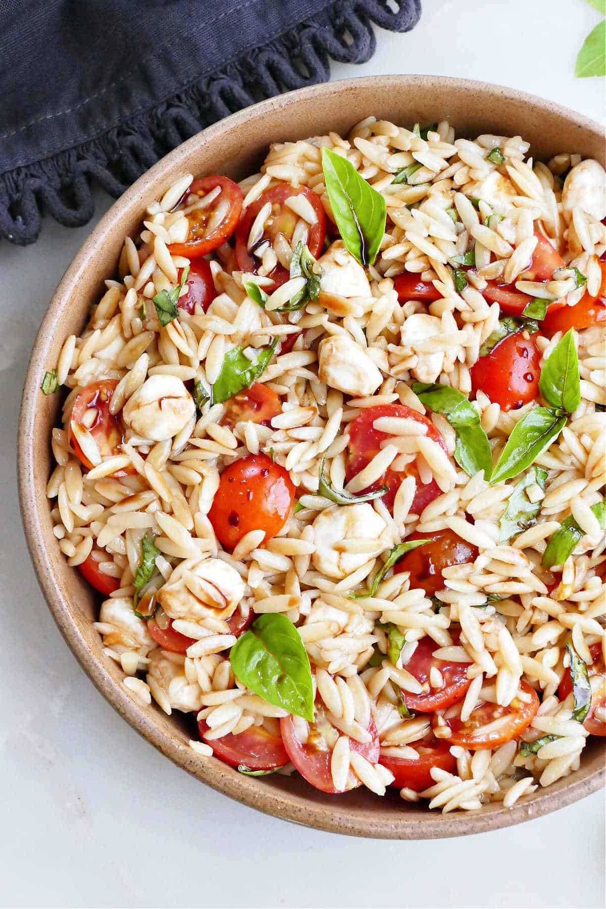 balsamic orzo salad with tomatoes and basil in a bowl on a counter