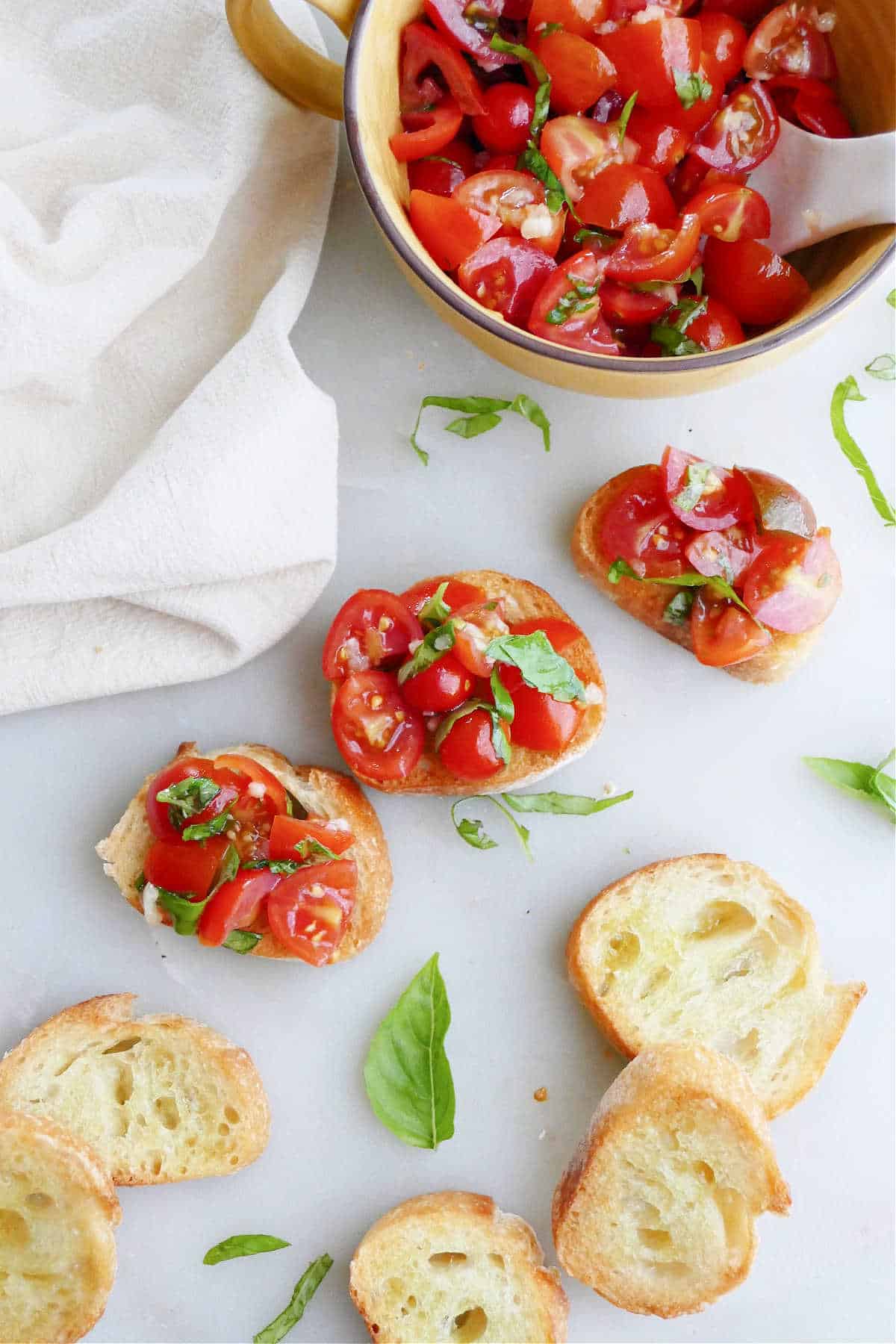 three cherry tomato bruschetta slices next to plain bread slices and topping