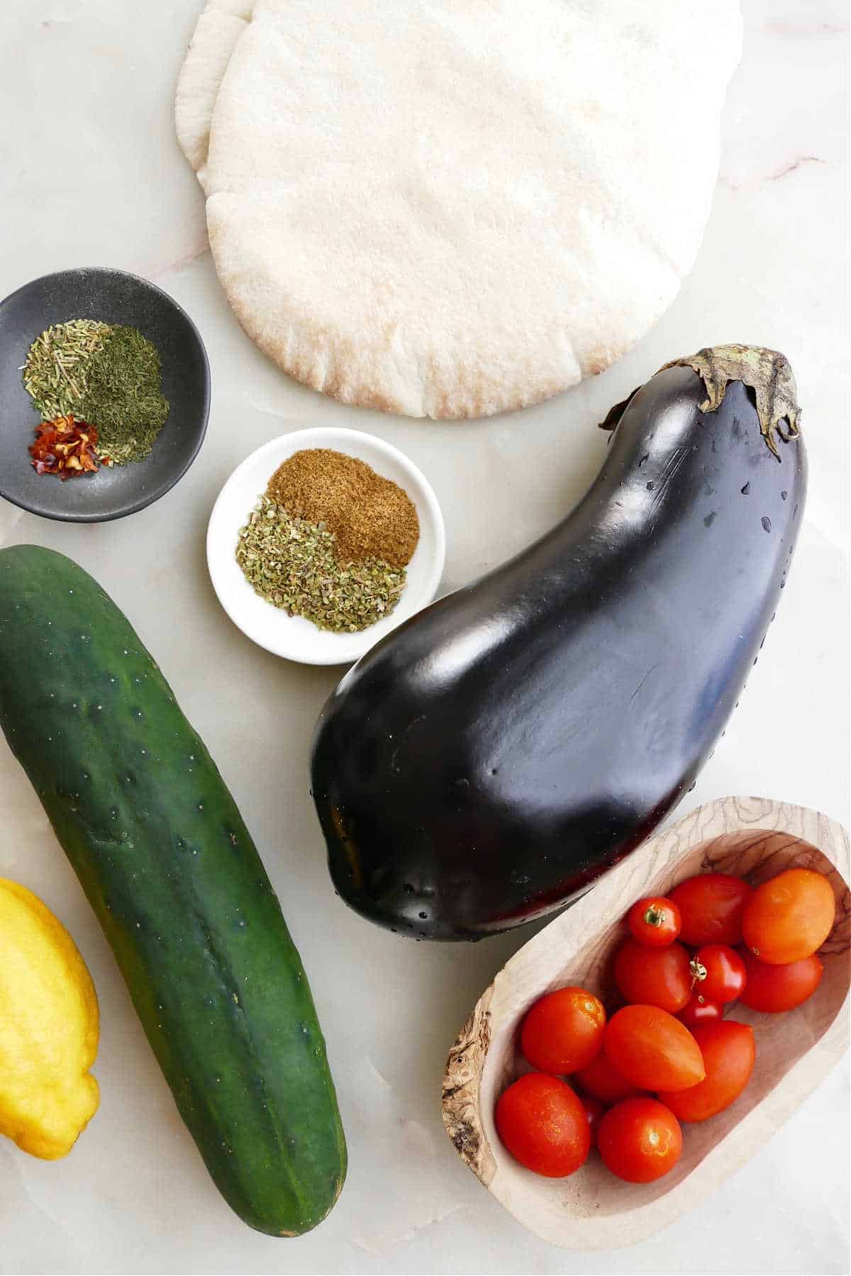 ingredients for eggplant gyro sandwiches spread out next to each other on a counter