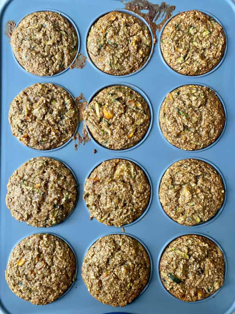 muffin tin with zucchini carrot oat muffins after being pulled out of the oven