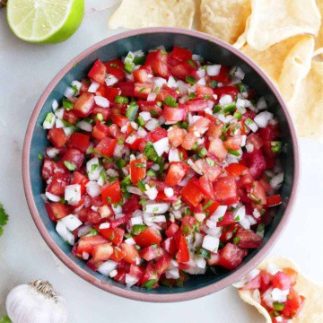 fresh garden salsa in a serving bowl surrounded by tortilla chips and ingredients