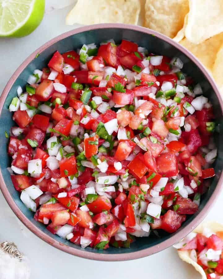 fresh garden salsa in a serving bowl surrounded by tortilla chips and ingredients