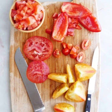 cutting board with different varieties of tomatoes cut into different shapes