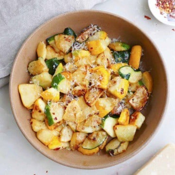 sauteed patty pan squash with parmesan cheese in a serving bowl on a counter