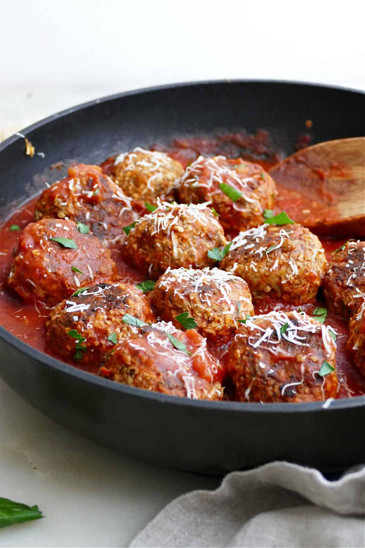 eggplant meatballs in a skillet simmering in tomato sauce and topped with parsley