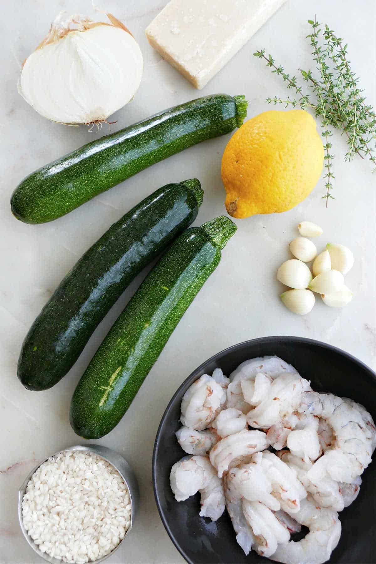 onion, zucchini, lemon, garlic, thyme, rice, and shrimp on a counter