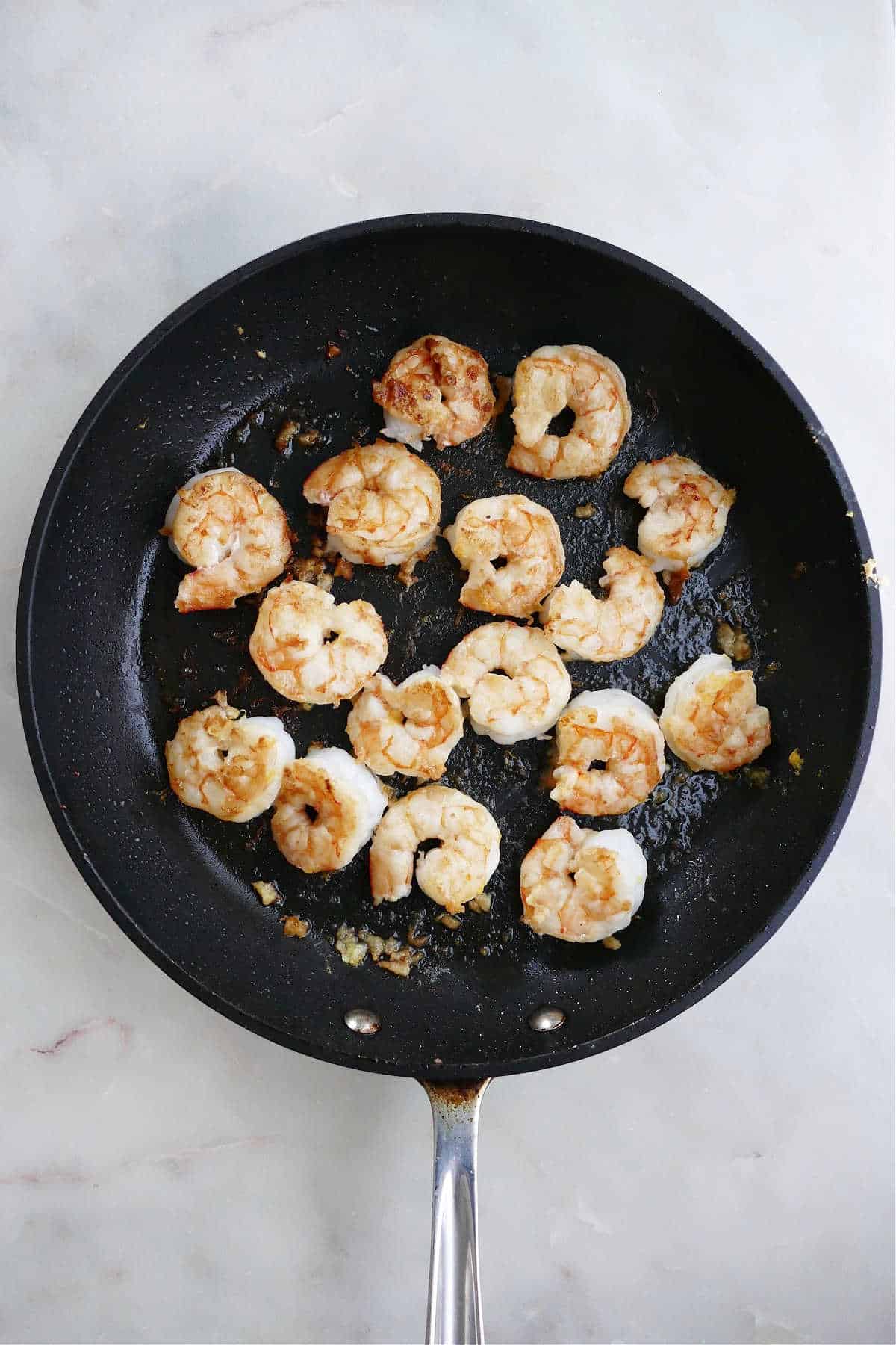 shrimp cooking in lemon garlic butter in a skillet on a counter