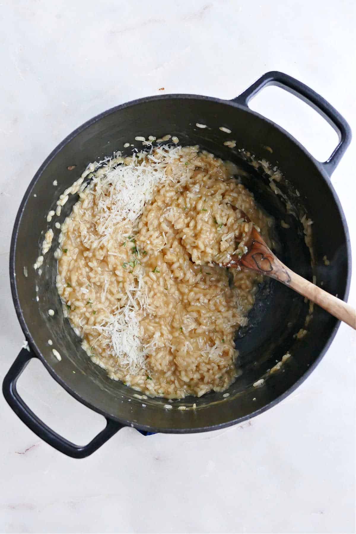 creamy risotto cooking in a Dutch oven with added parmesan cheese and thyme