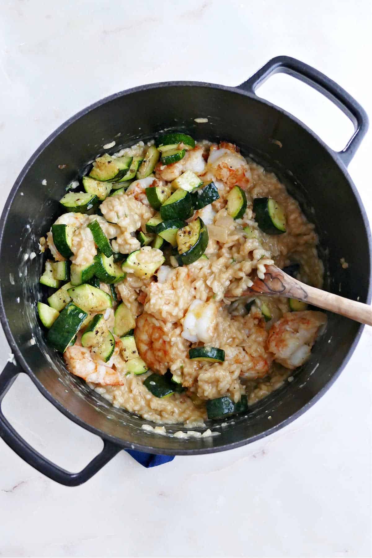 risotto cooking in a Dutch oven with zucchini and shrimp mixed into it
