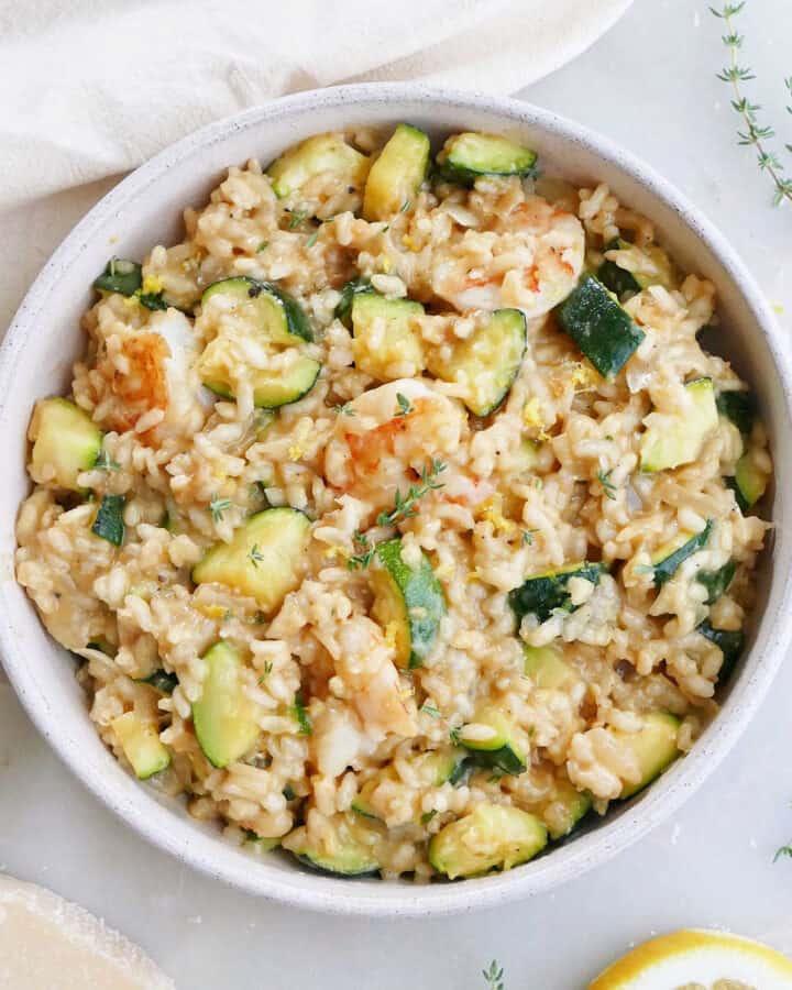 zucchini risotto with shrimp in a serving dish on a counter next to ingredients