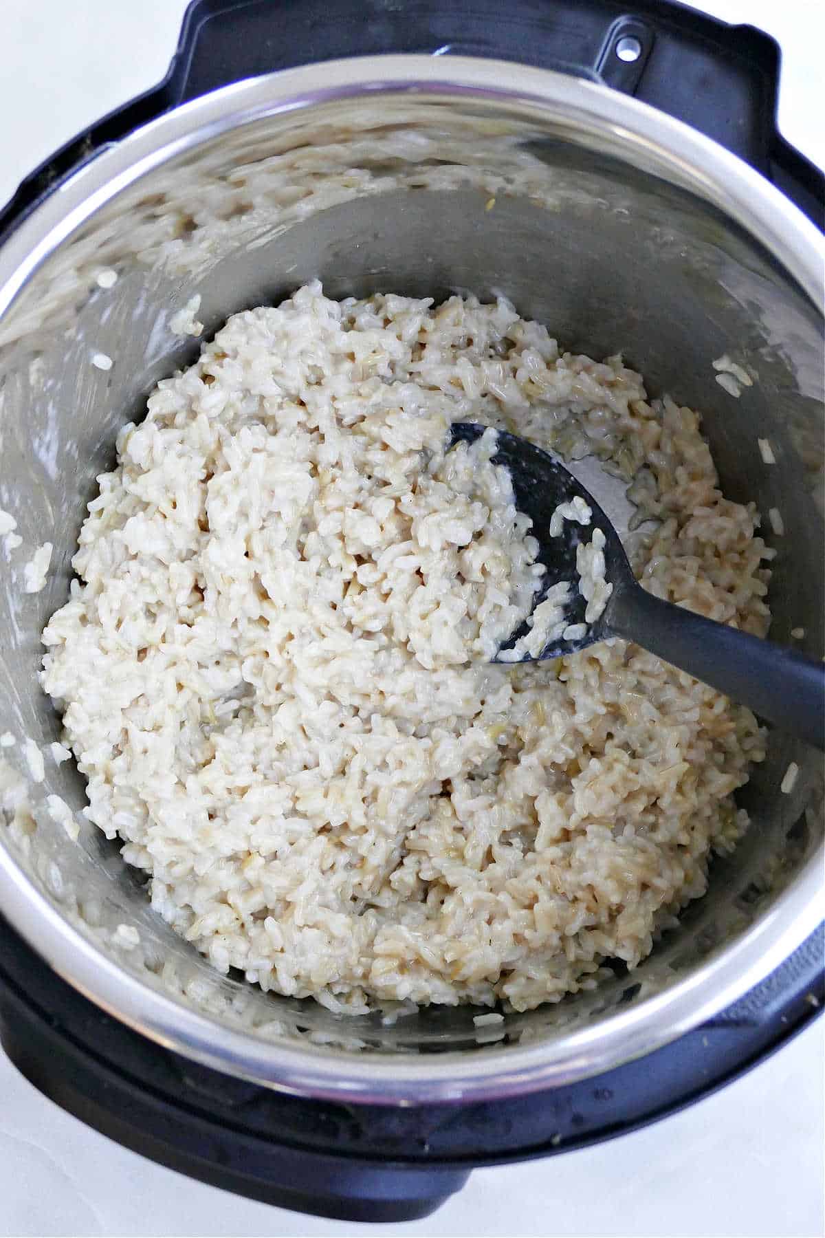 cooked coconut rice in the Instant Pot with a spoon sitting on a counter