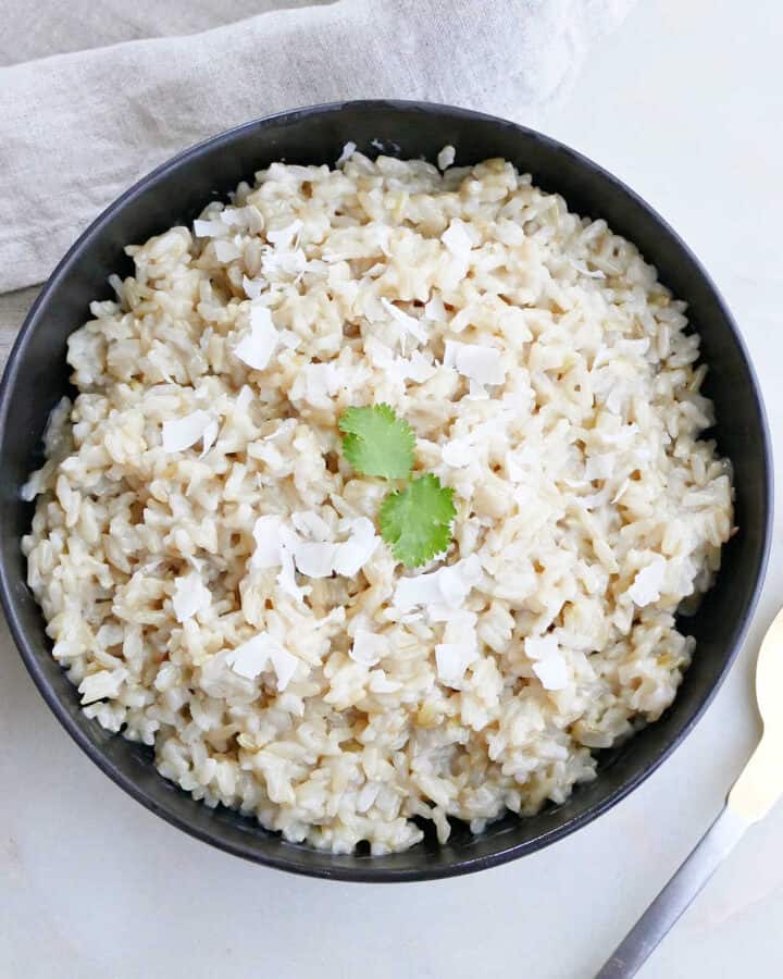 Instant Pot coconut brown rice topped with cilantro and coconut flakes in a serving bowl