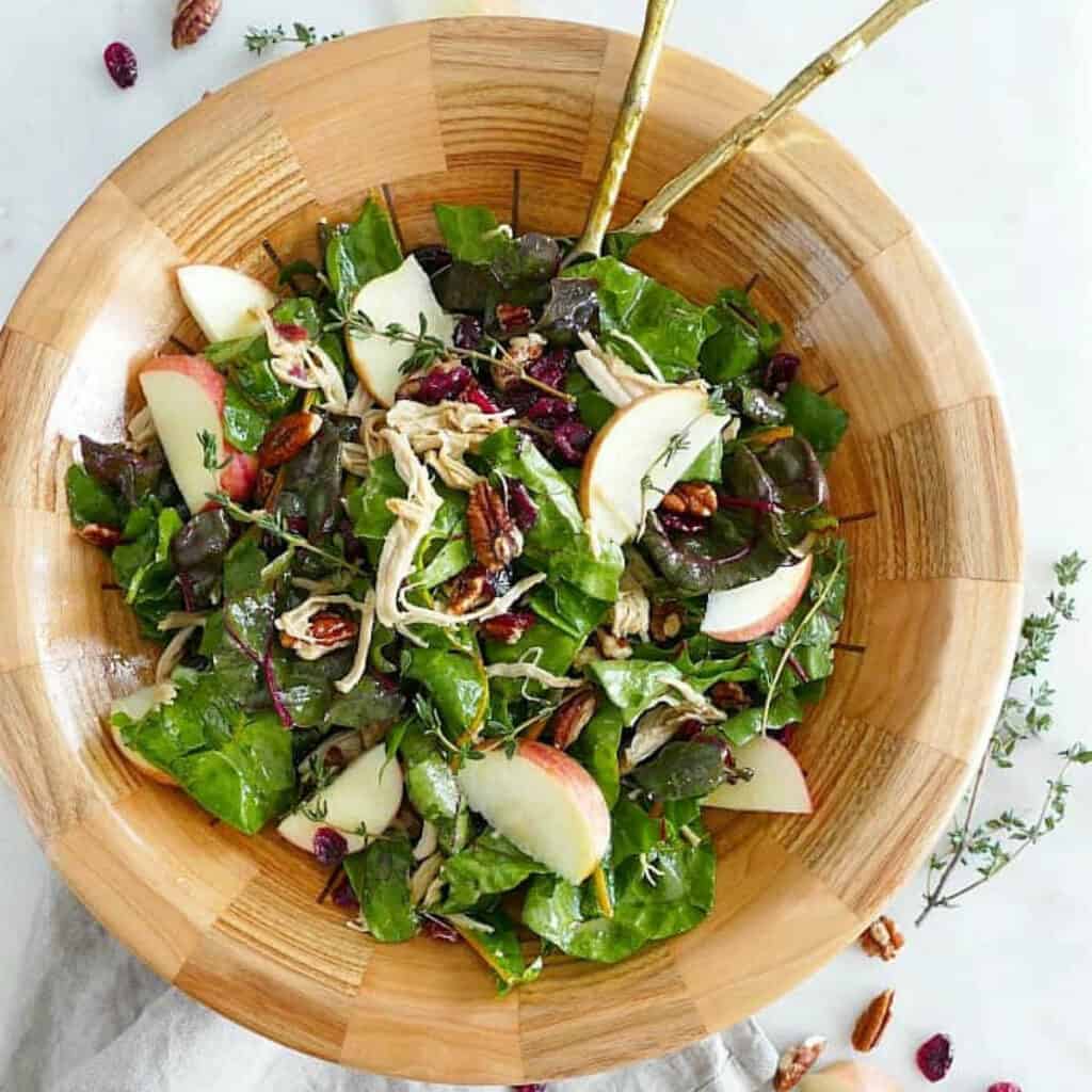 maple swiss chard salad with turkey in a bowl with salad utensils