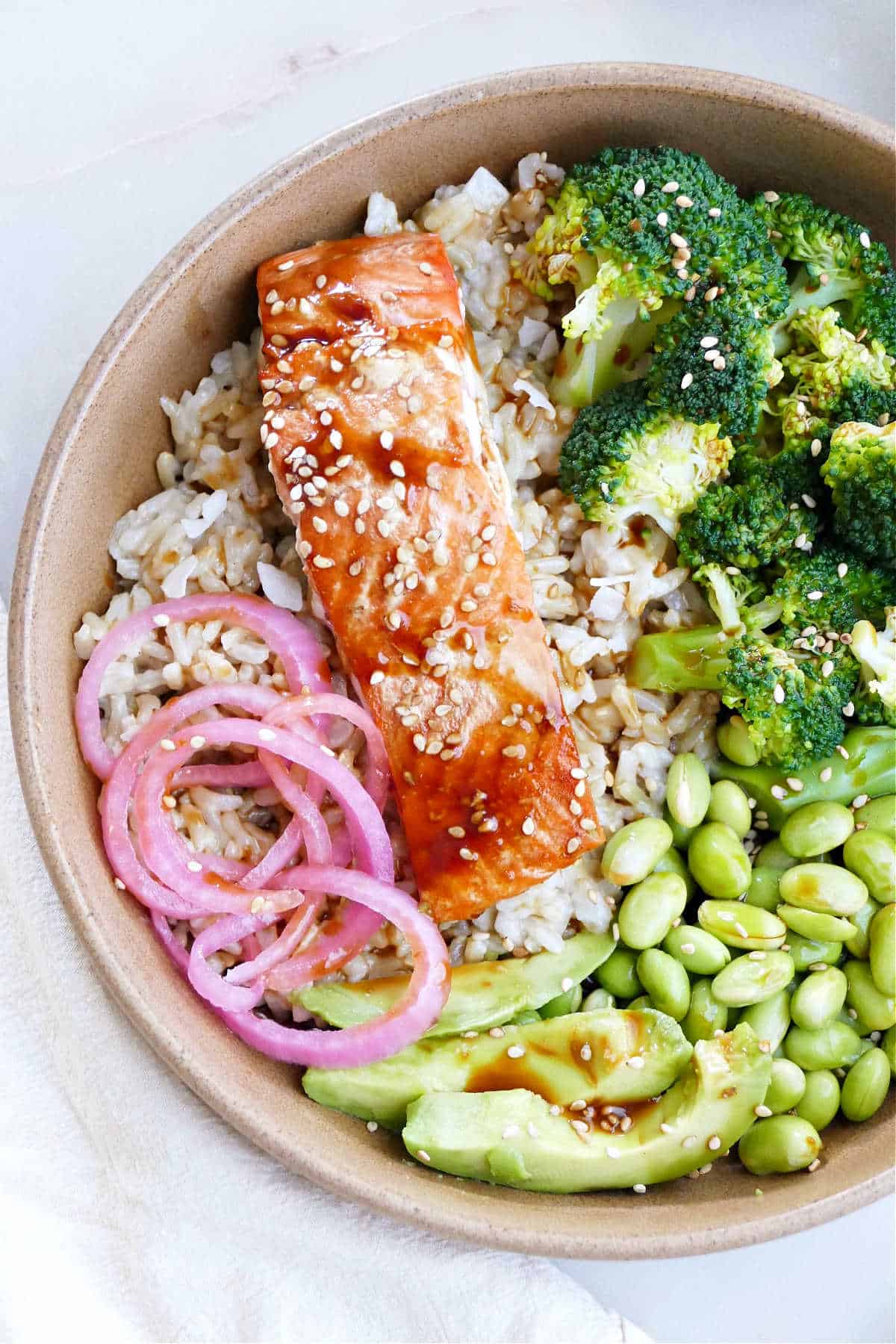 teriyaki salmon, pickled onions, broccoli, edamame, and avocado over rice in a serving bowl