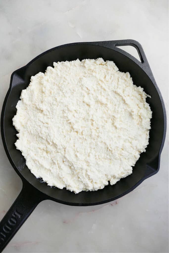 ricotta dip spread out in an 8-inch cast iron skillet on a counter