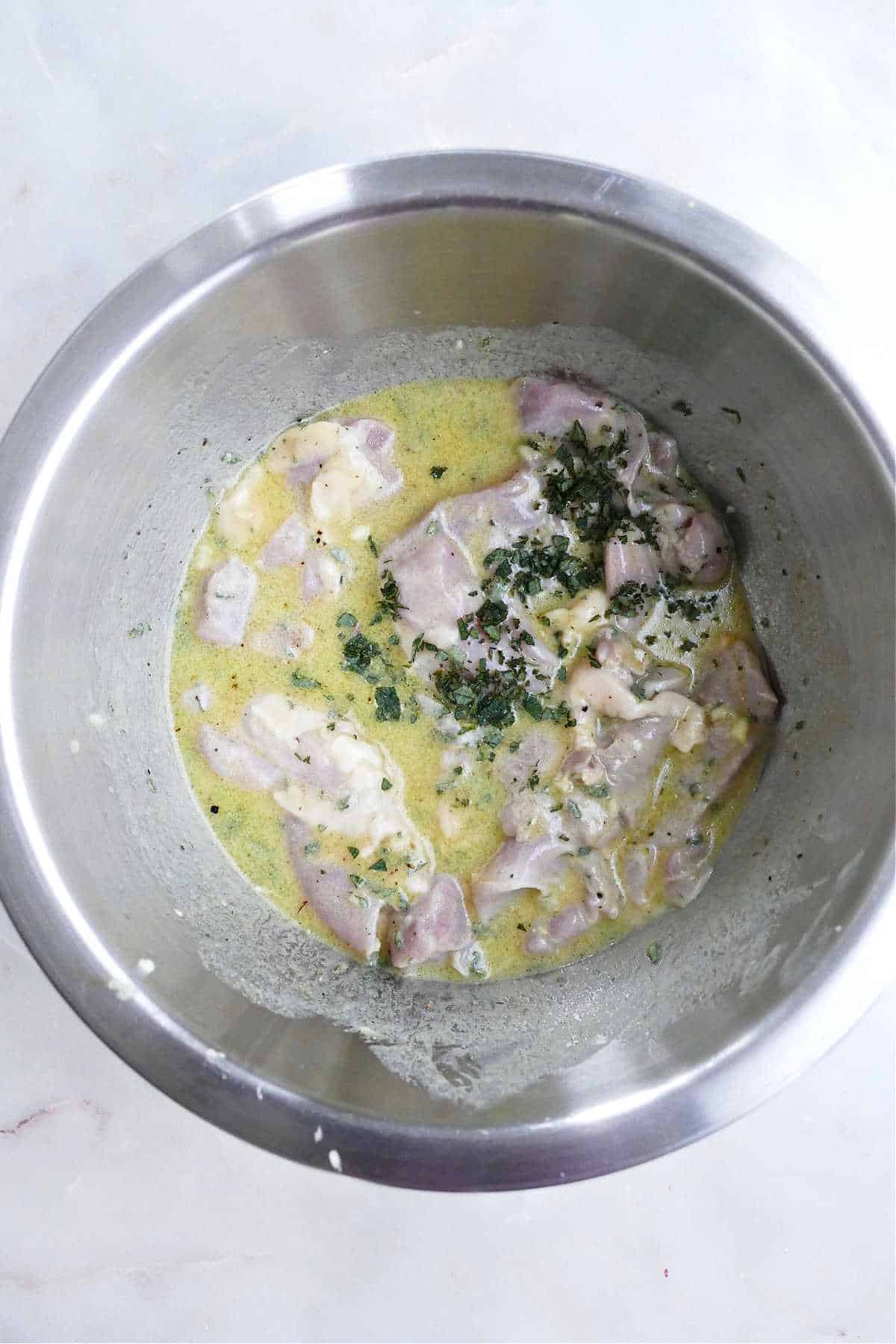 chicken thighs marinating in a mustard maple dressing in a large mixing bowl
