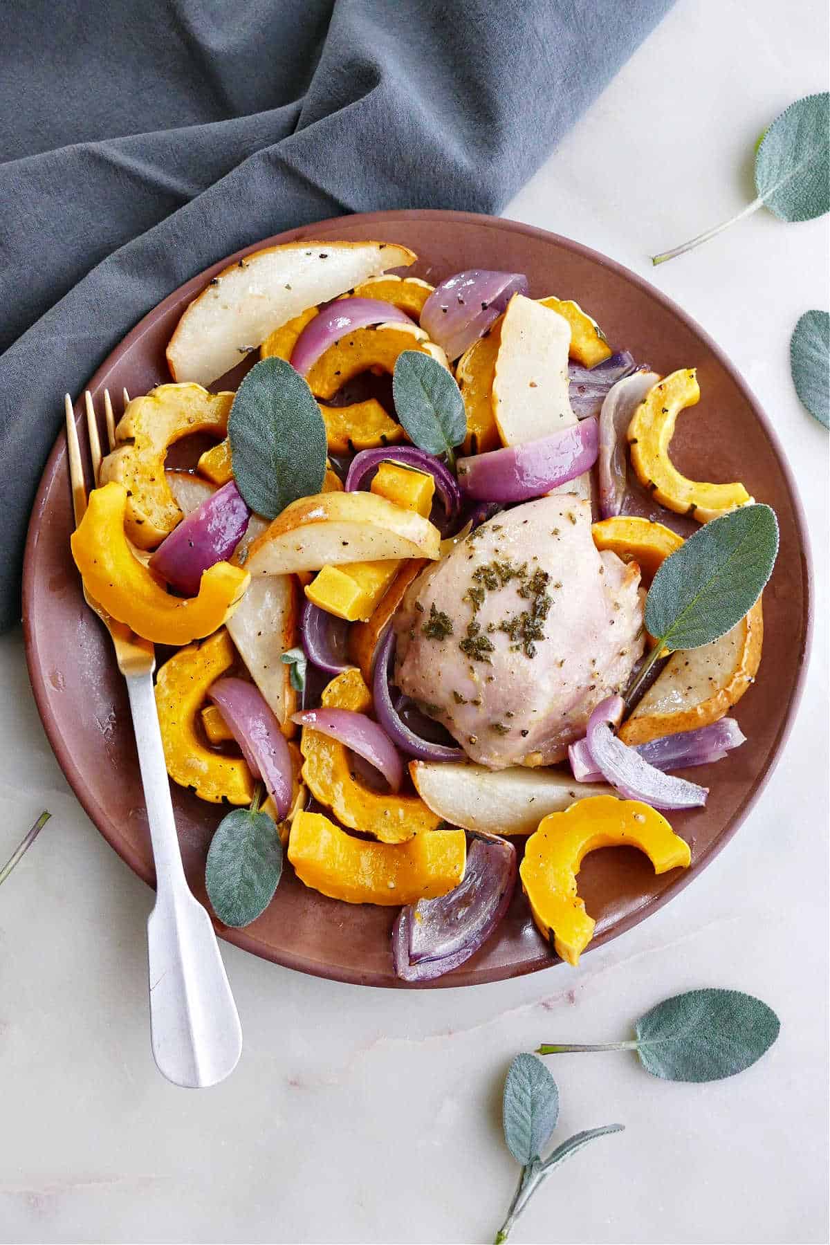 delicata squash and chicken meal on a serving plate with a fork and sage leaves