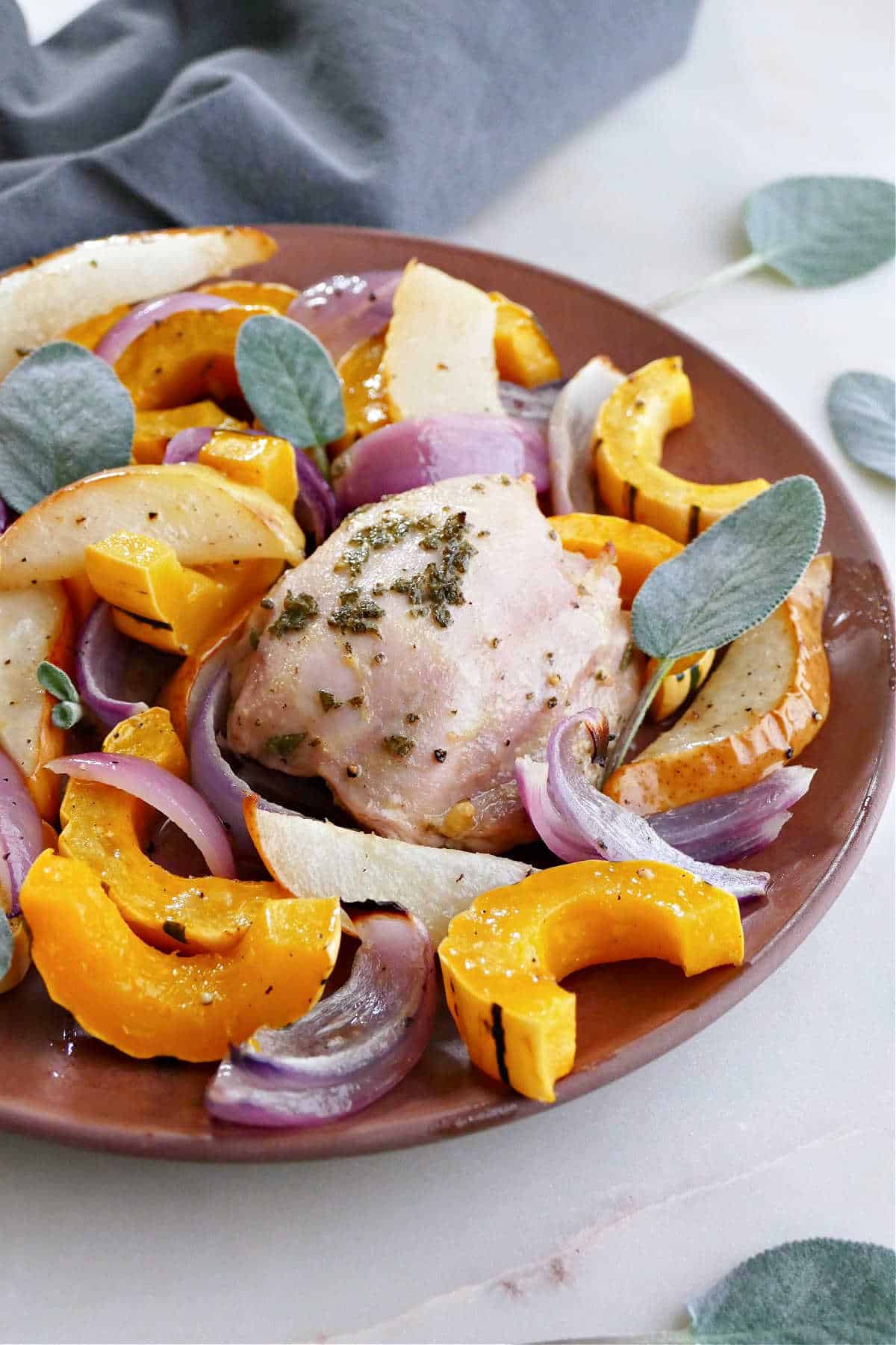 chicken, squash, pears, onions, and sage on a serving plate on a counter