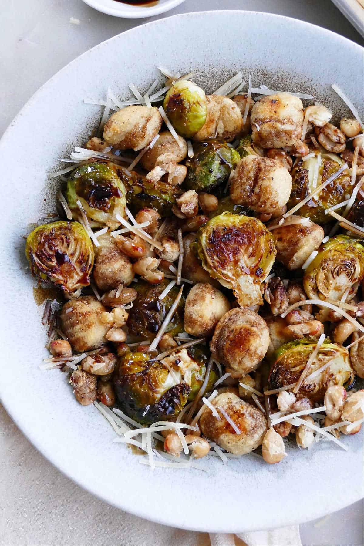 gnocchi, Brussels sprouts, and white beans in a serving bowl topped with parmesan and balsamic reduction