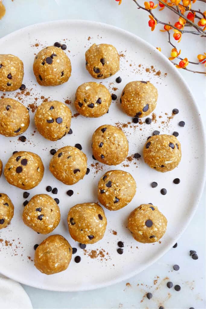 pumpkin peanut butter balls on a serving plate with chocolate chips and cinnamon