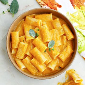 slow cooker butternut squash mac and cheese in a serving bowl topped with sage and thyme