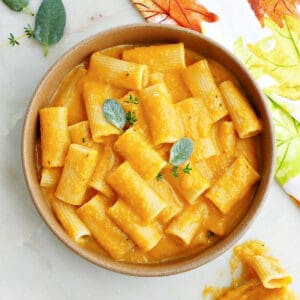 slow cooker butternut squash mac and cheese in a serving bowl topped with sage and thyme