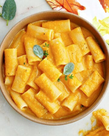 slow cooker butternut squash mac and cheese in a serving bowl topped with sage and thyme