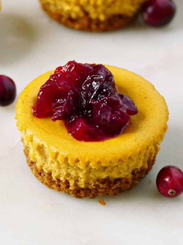 mini cranberry pumpkin cheesecake with graham cracker crust on a counter