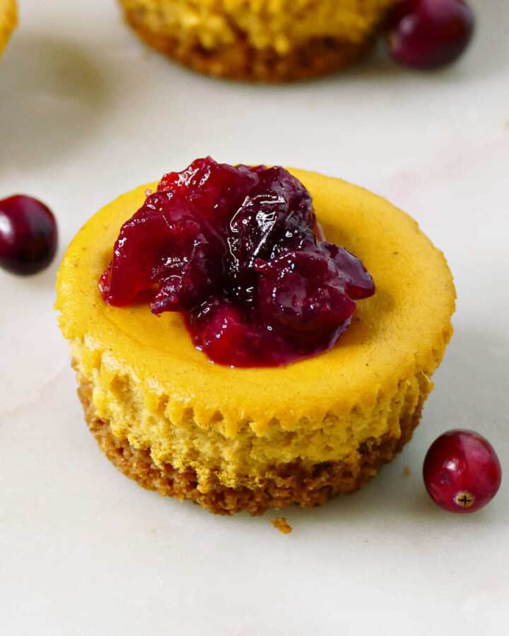 mini cranberry pumpkin cheesecake with graham cracker crust on a counter