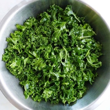 massaged kale softened with olive oil in a mixing bowl on a counter