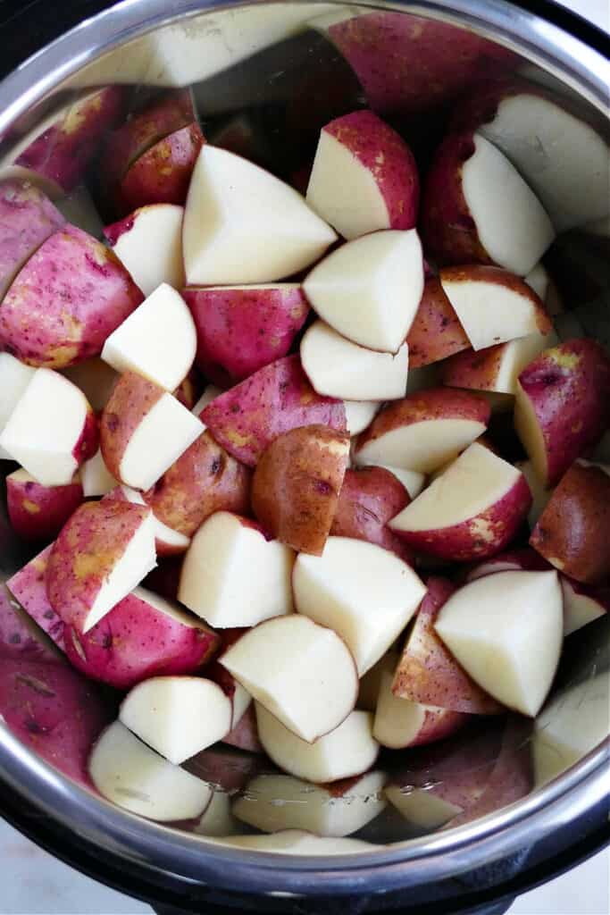 sliced red potatoes with broth in a pressure cooker on a counter