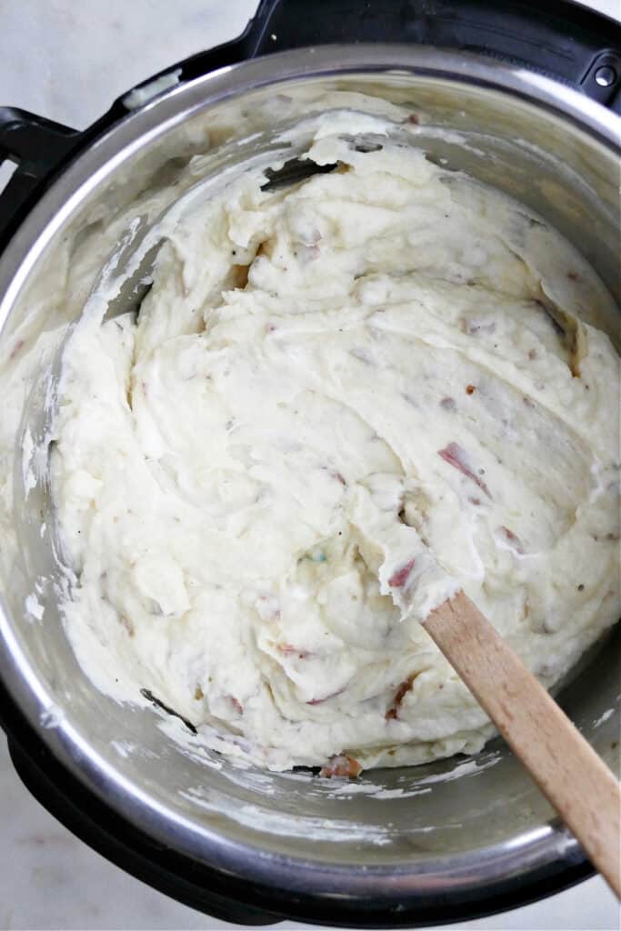 Instant Pot mashed red potatoes being mixed with a rubber spatula