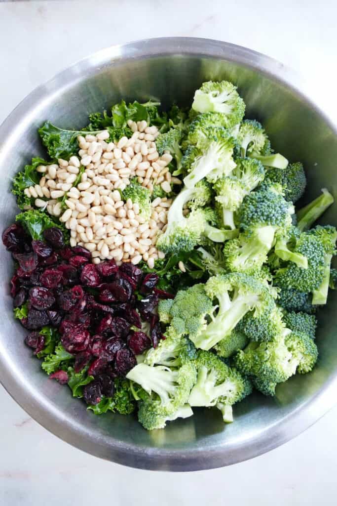 kale, broccoli, pine nuts, and dried cranberries in a large mixing bowl