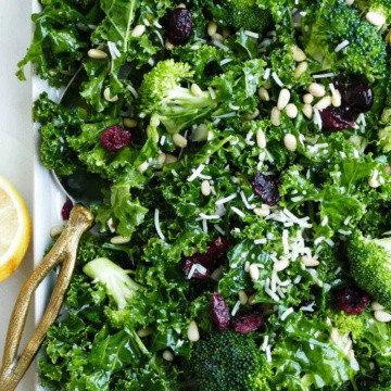 kale and broccoli salad on a serving platter with a gold serving spoon