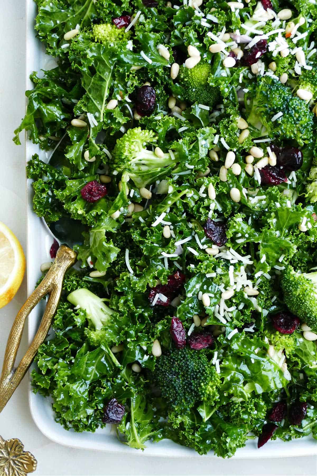 kale and broccoli salad on a serving platter with a gold serving spoon