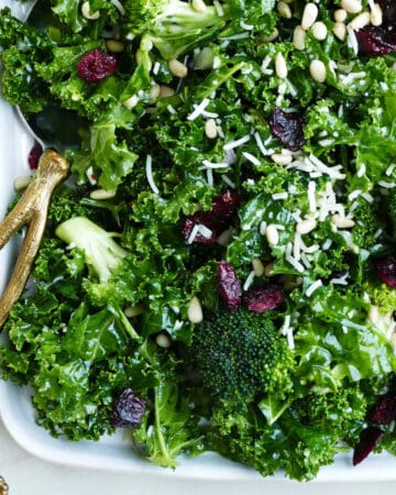 kale and broccoli salad on a serving platter with a gold serving spoon