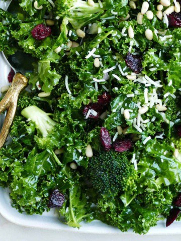 kale and broccoli salad on a serving platter with a gold serving spoon