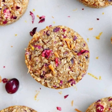 orange carrot muffins made with oatmeal on a counter next to fresh cranberries