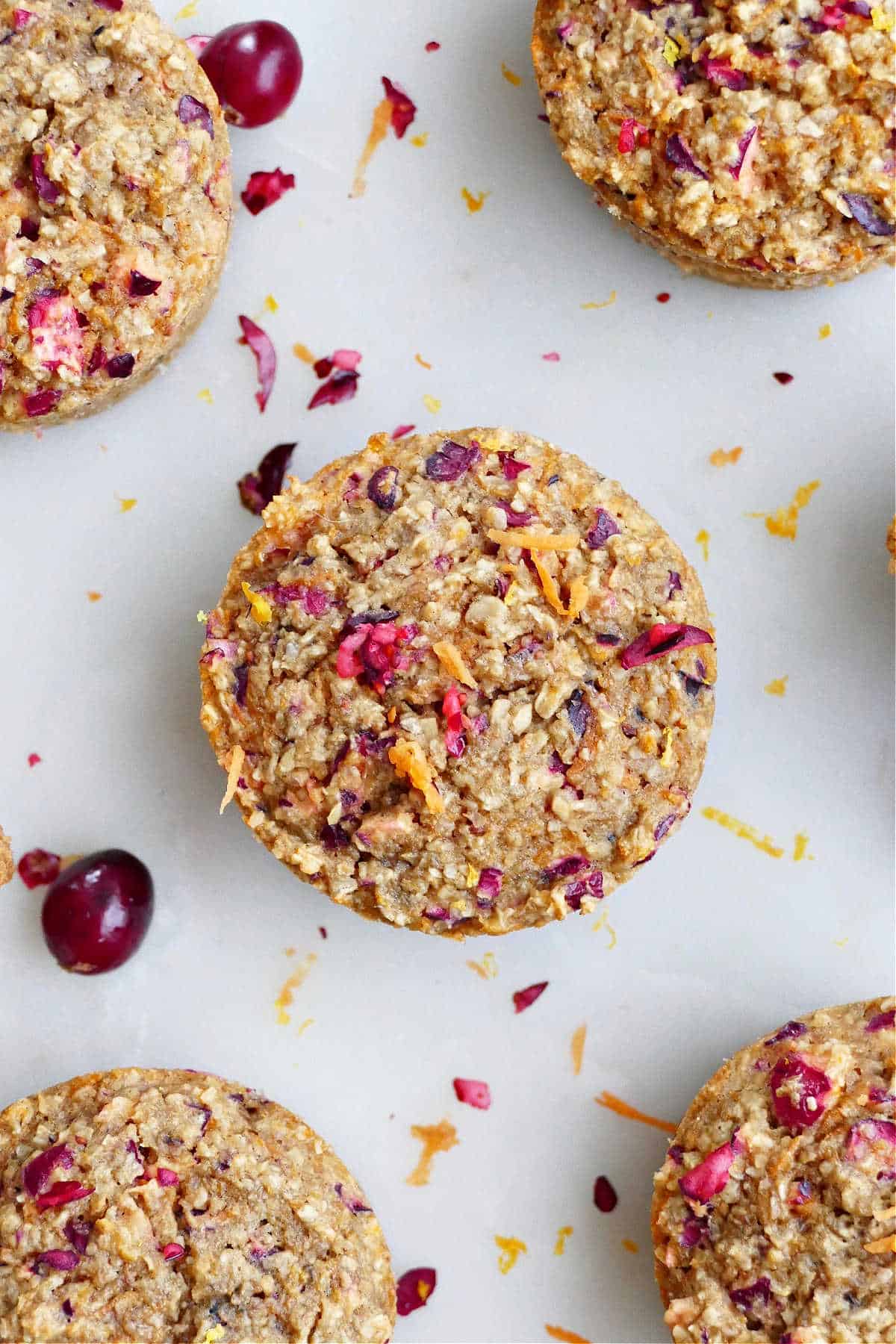 orange carrot muffins made with oatmeal on a counter next to fresh cranberries