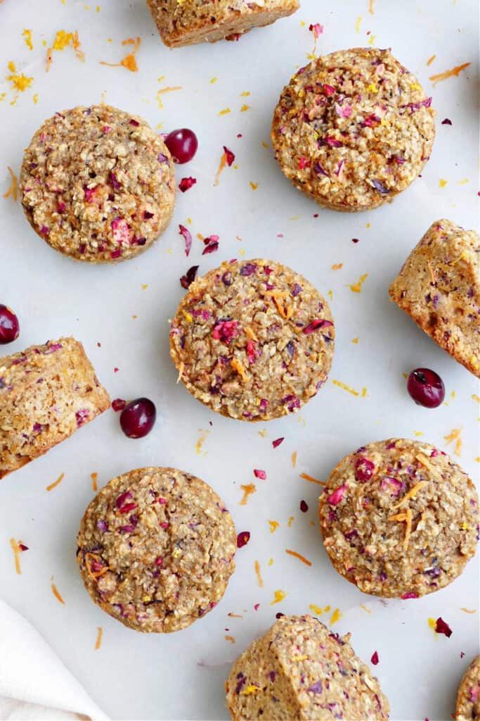 oatmeal orange carrot muffins with cranberries spread out next to each other on a counter